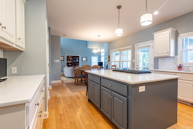 kitchen with light wood-style flooring, gray cabinetry, a center island, white cabinets, and decorative backsplash