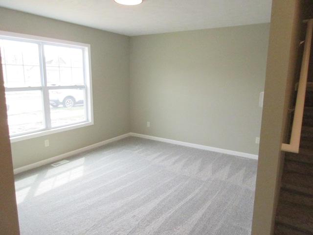 unfurnished room featuring carpet floors, stairway, baseboards, and visible vents