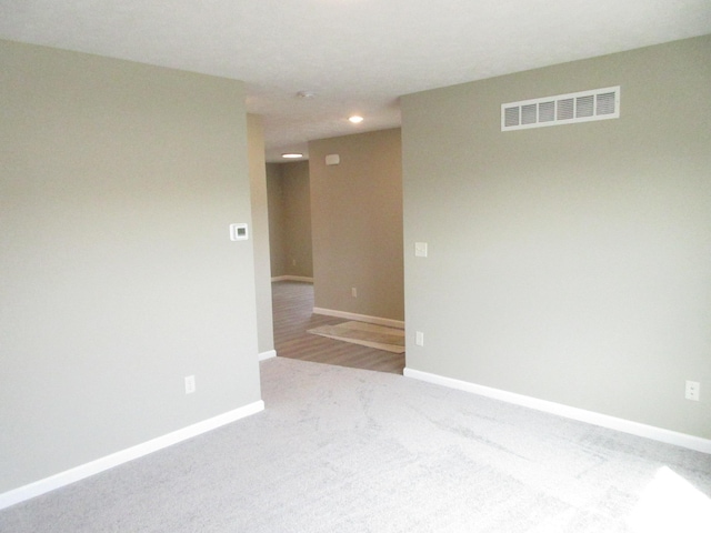 carpeted empty room featuring baseboards and visible vents