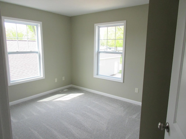 spare room with carpet floors, visible vents, and baseboards