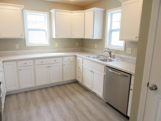 kitchen with a sink, light wood-style floors, white cabinets, light countertops, and dishwasher