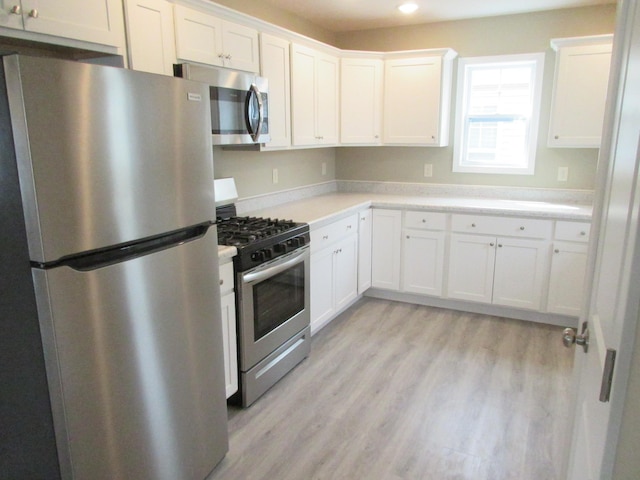 kitchen featuring light wood-type flooring, white cabinetry, stainless steel appliances, and light countertops