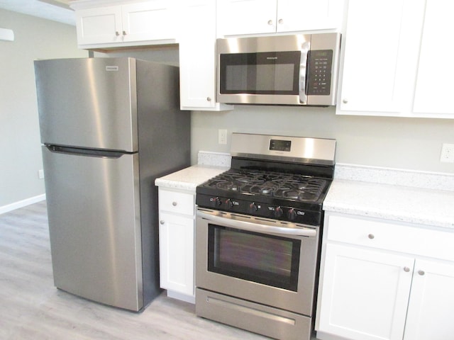 kitchen with baseboards, white cabinets, light stone countertops, stainless steel appliances, and light wood-type flooring