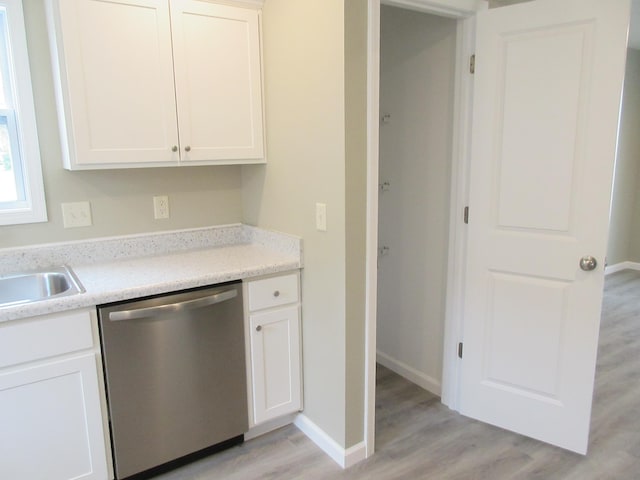 kitchen with light wood finished floors, stainless steel dishwasher, white cabinetry, and baseboards