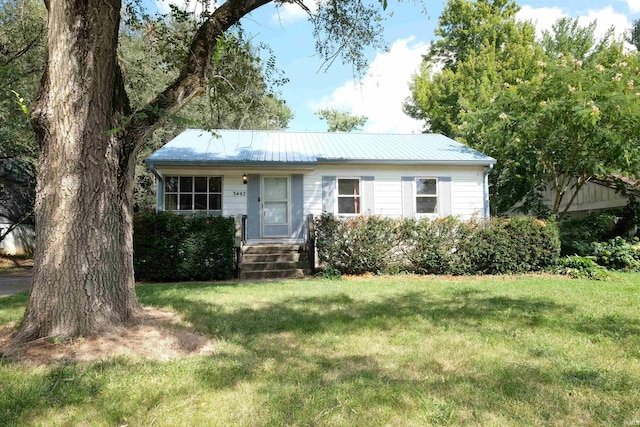 view of front of property featuring metal roof and a front yard