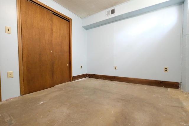 unfurnished bedroom featuring baseboards, visible vents, concrete flooring, and a closet