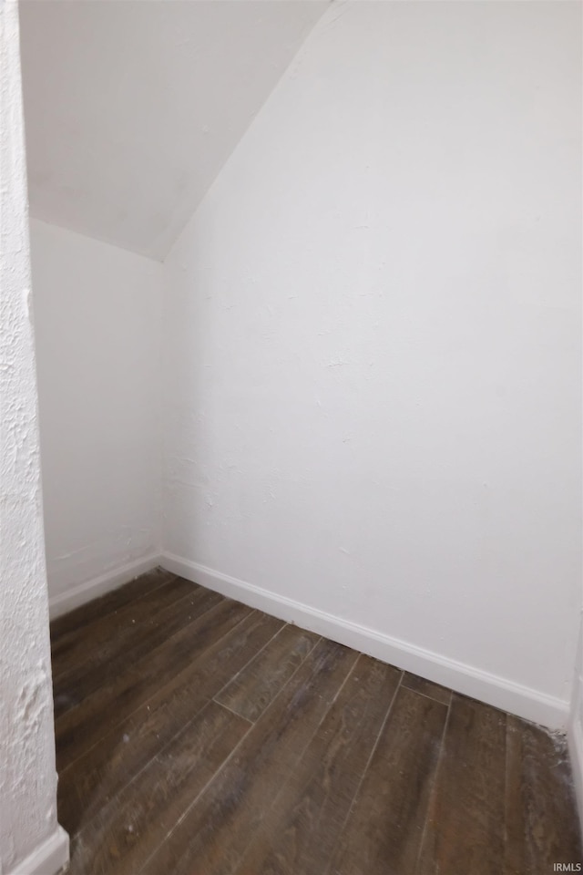 interior space featuring lofted ceiling, dark wood finished floors, and baseboards