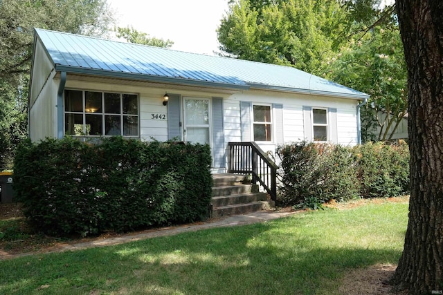 view of front of property with metal roof and a front lawn