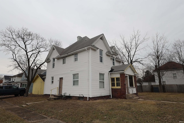 view of side of property with a yard, entry steps, fence, and a chimney