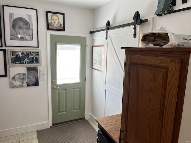 doorway with a barn door, light tile patterned flooring, and baseboards