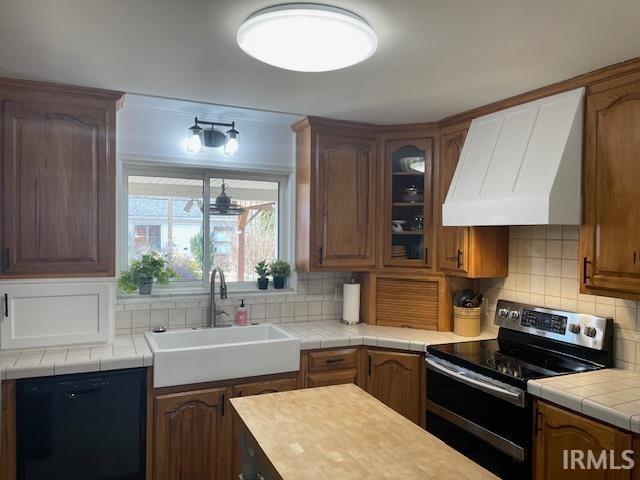 kitchen with custom exhaust hood, decorative backsplash, stainless steel range with electric cooktop, a sink, and dishwasher