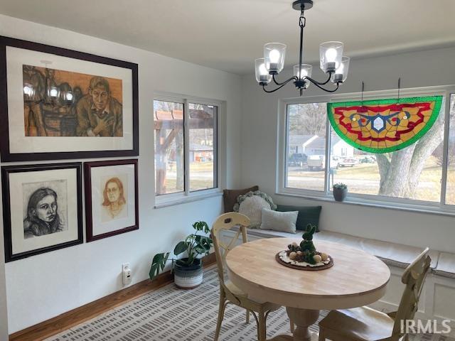 dining room featuring wood finished floors, baseboards, and an inviting chandelier