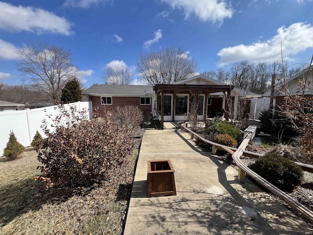 rear view of property featuring a patio area, brick siding, and fence