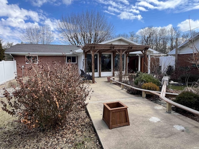 rear view of property with a shingled roof, a fire pit, fence, a patio area, and brick siding