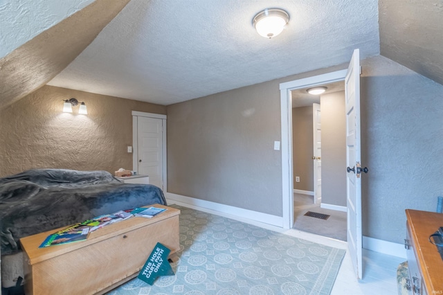 bedroom featuring visible vents, a textured wall, a textured ceiling, and baseboards