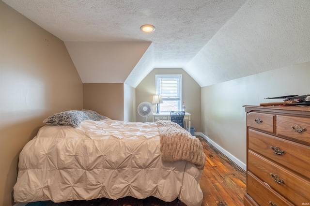 bedroom featuring lofted ceiling, a textured ceiling, dark wood finished floors, and baseboards