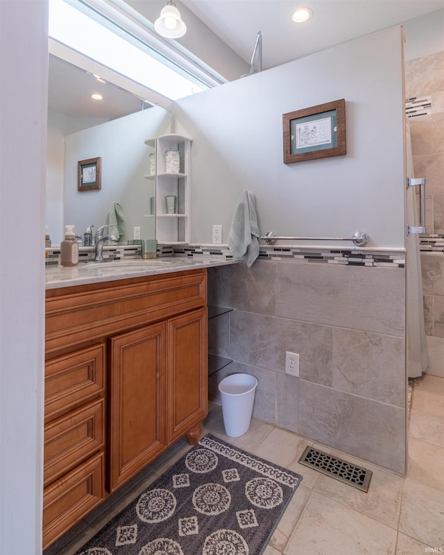 full bathroom with tile walls, visible vents, a tile shower, vanity, and tile patterned flooring