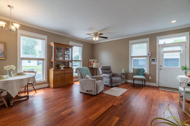 living room with baseboards, ceiling fan with notable chandelier, wood finished floors, and crown molding