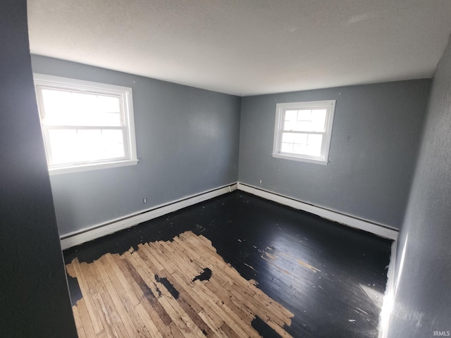 empty room with a baseboard heating unit and wood finished floors