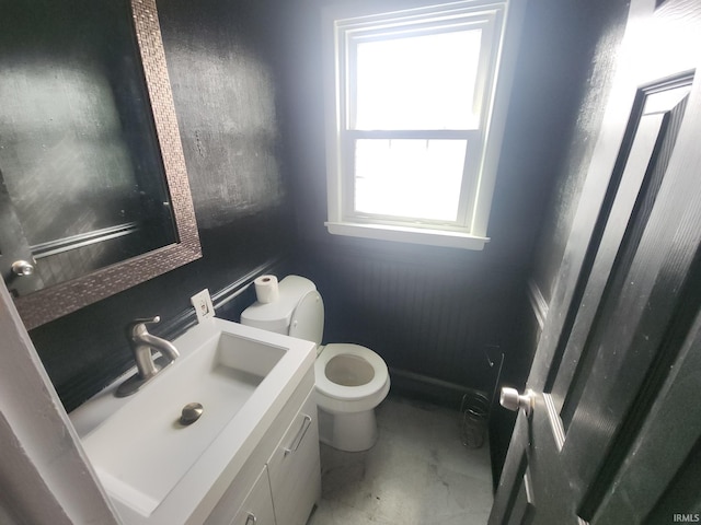 half bath with marble finish floor, vanity, and toilet