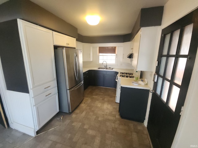 kitchen featuring gas range gas stove, light countertops, freestanding refrigerator, white cabinetry, and a sink