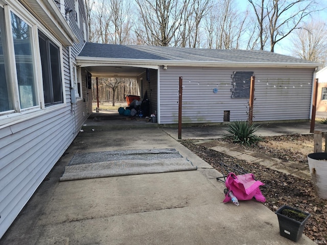 view of property exterior featuring a shingled roof and an attached carport