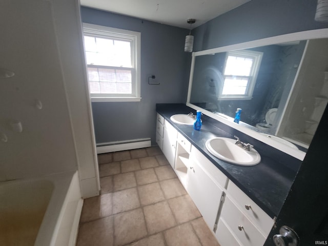 bathroom with a tub to relax in, a baseboard radiator, a sink, and double vanity