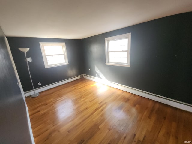 unfurnished room with a baseboard radiator, baseboards, and wood finished floors