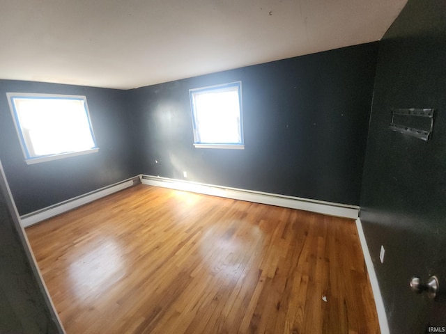 empty room featuring a baseboard radiator, wood finished floors, and baseboards