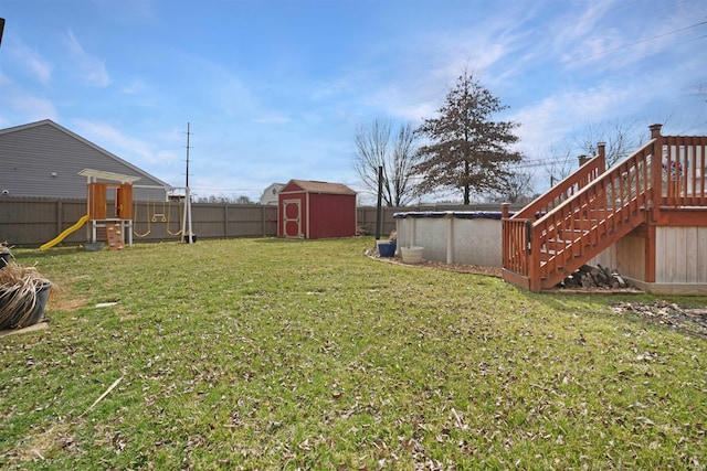 view of yard featuring an outdoor pool, a fenced backyard, a storage unit, an outdoor structure, and a playground