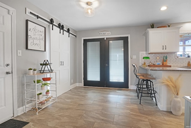 interior space with french doors, a barn door, and baseboards