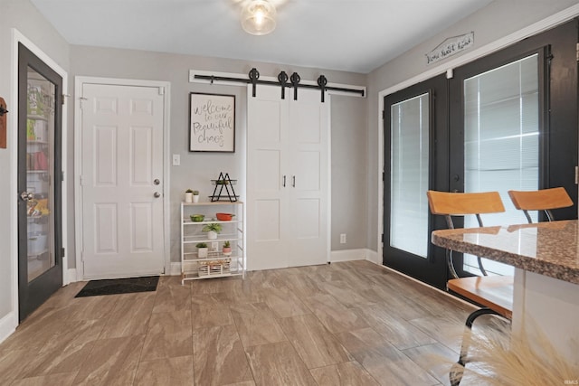 foyer featuring french doors, baseboards, and a barn door