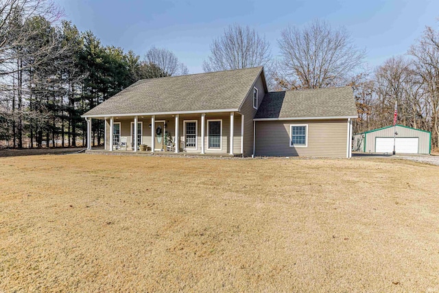 view of front of home featuring a shingled roof, a detached garage, a porch, an outbuilding, and a front lawn