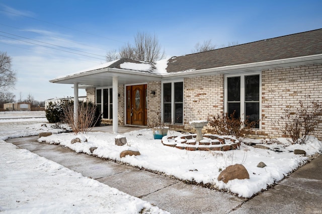 view of front of house with brick siding and roof with shingles