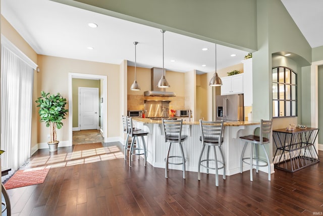 kitchen featuring a peninsula, appliances with stainless steel finishes, dark wood-type flooring, and light stone counters