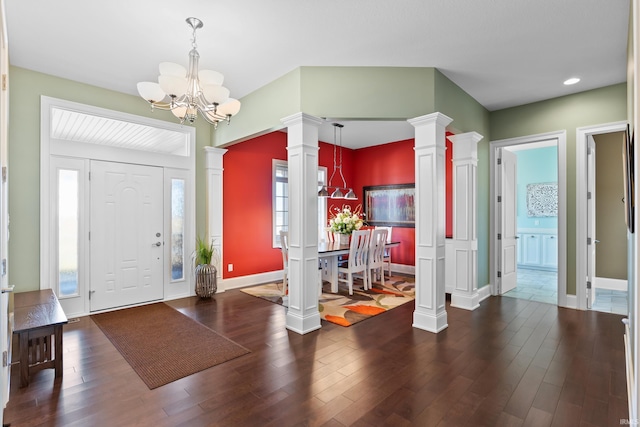 entrance foyer featuring baseboards, an inviting chandelier, wood finished floors, and ornate columns