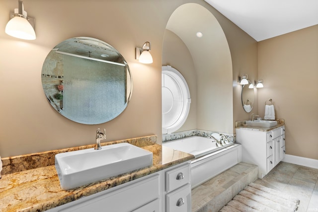 full bathroom featuring walk in shower, two vanities, a sink, and a bath