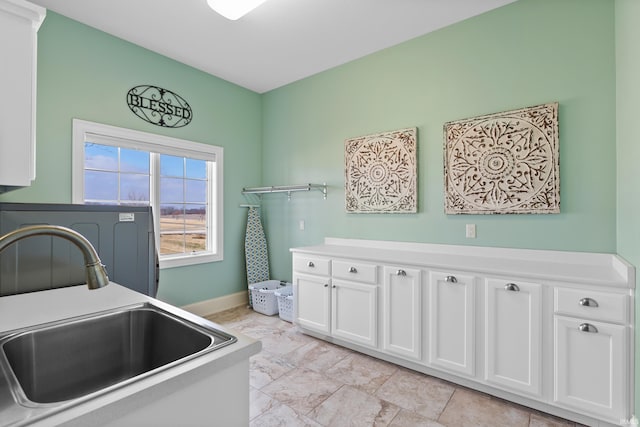 laundry area with a sink, cabinet space, and baseboards