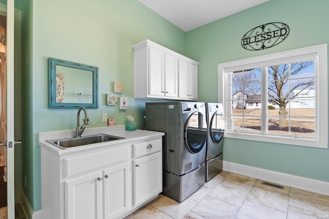 washroom featuring washing machine and clothes dryer, cabinet space, visible vents, a sink, and baseboards