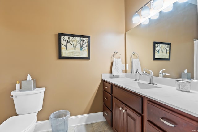 bathroom featuring toilet, baseboards, and vanity