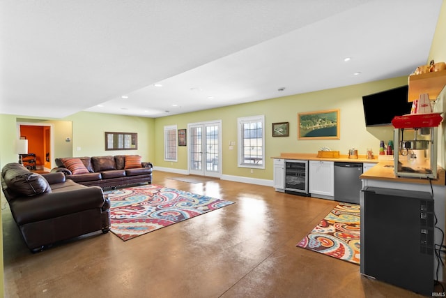 living area with concrete flooring, recessed lighting, beverage cooler, baseboards, and wet bar