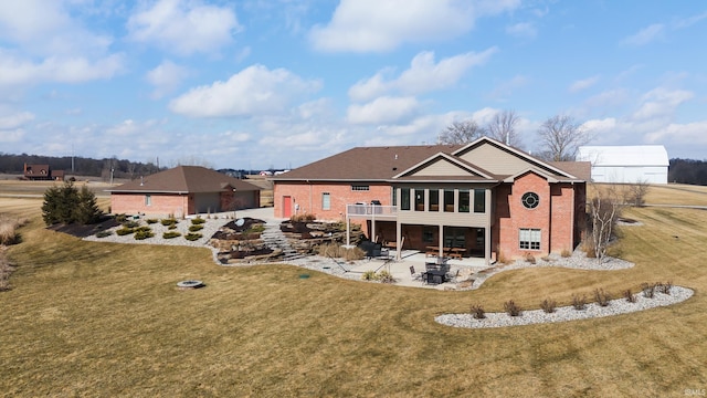 rear view of house with brick siding, a lawn, and a patio