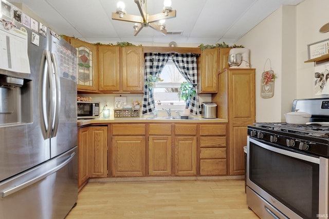 kitchen with stainless steel appliances, a sink, visible vents, light wood-style floors, and light countertops