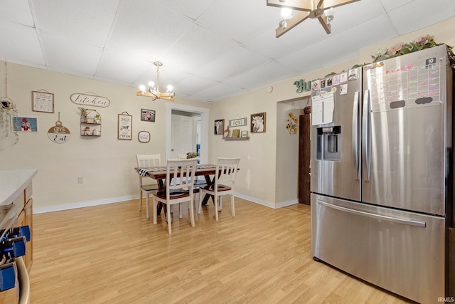 dining area featuring light wood-type flooring, a paneled ceiling, baseboards, and an inviting chandelier