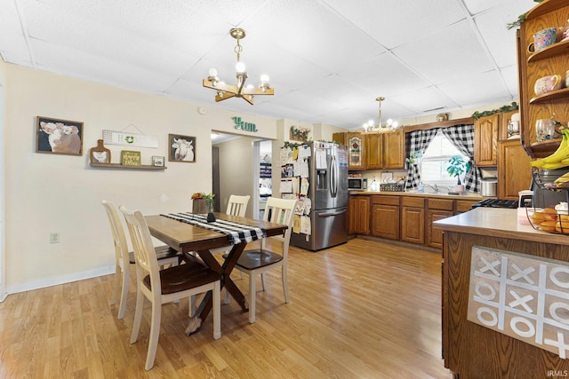 dining room featuring light wood-style floors, a paneled ceiling, and a notable chandelier