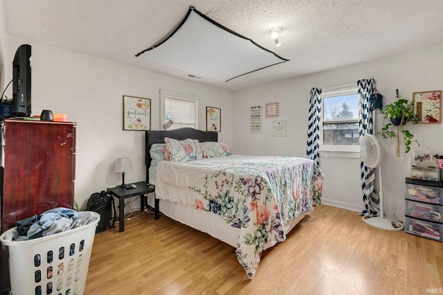 bedroom featuring a textured ceiling, light wood finished floors, and visible vents