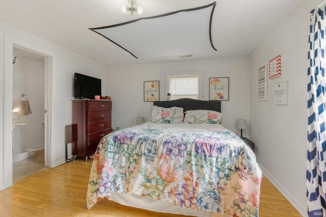 bedroom featuring visible vents, baseboards, and wood finished floors