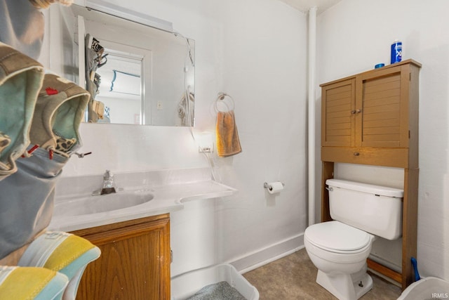 bathroom featuring toilet, baseboards, and vanity