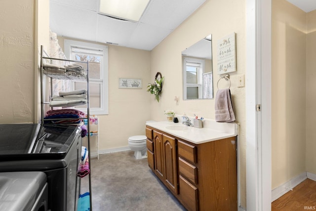 bathroom featuring toilet, baseboards, a paneled ceiling, and washer and dryer