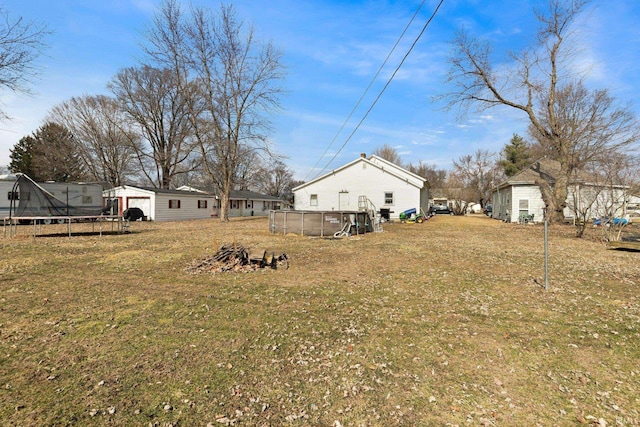 view of yard with a trampoline and an outdoor pool